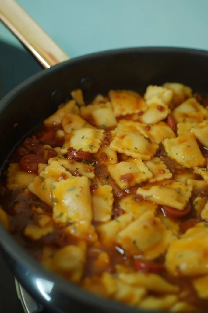 In this image, we see a typical Piedmontese stuffed pasta: agnolotti. They are in a pan with a flavorful roast sauce and Parmesan.