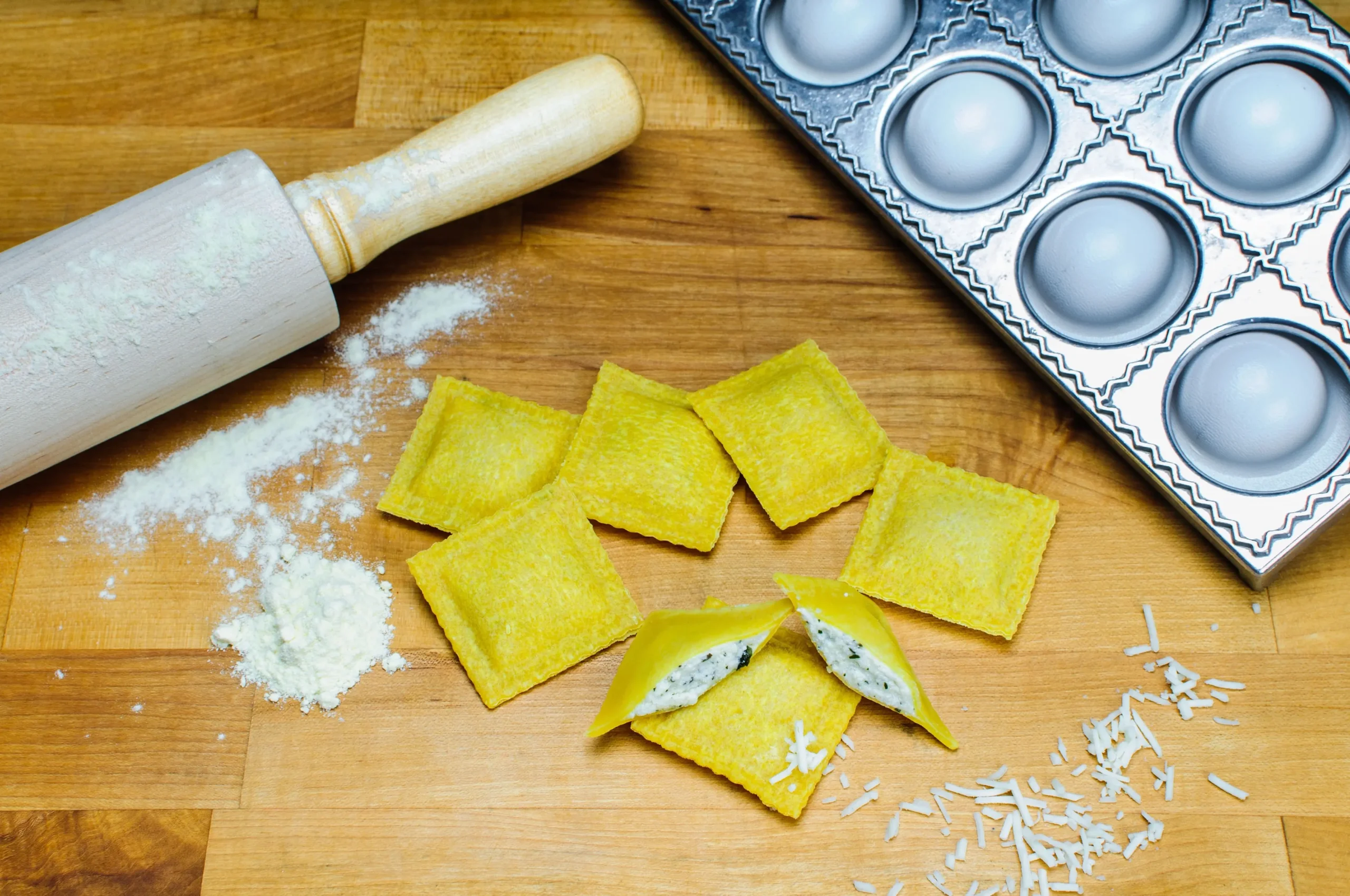 In this image, handmade ravioli with the classic ricotta and spinach filling are visible, waiting to be cooked.
